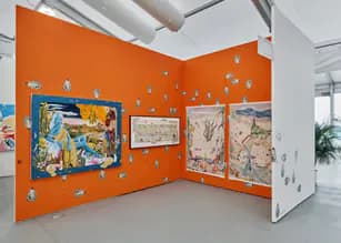 Interior gallery view with bright orange walls displaying framed artworks and geometric compositions in mixed media.