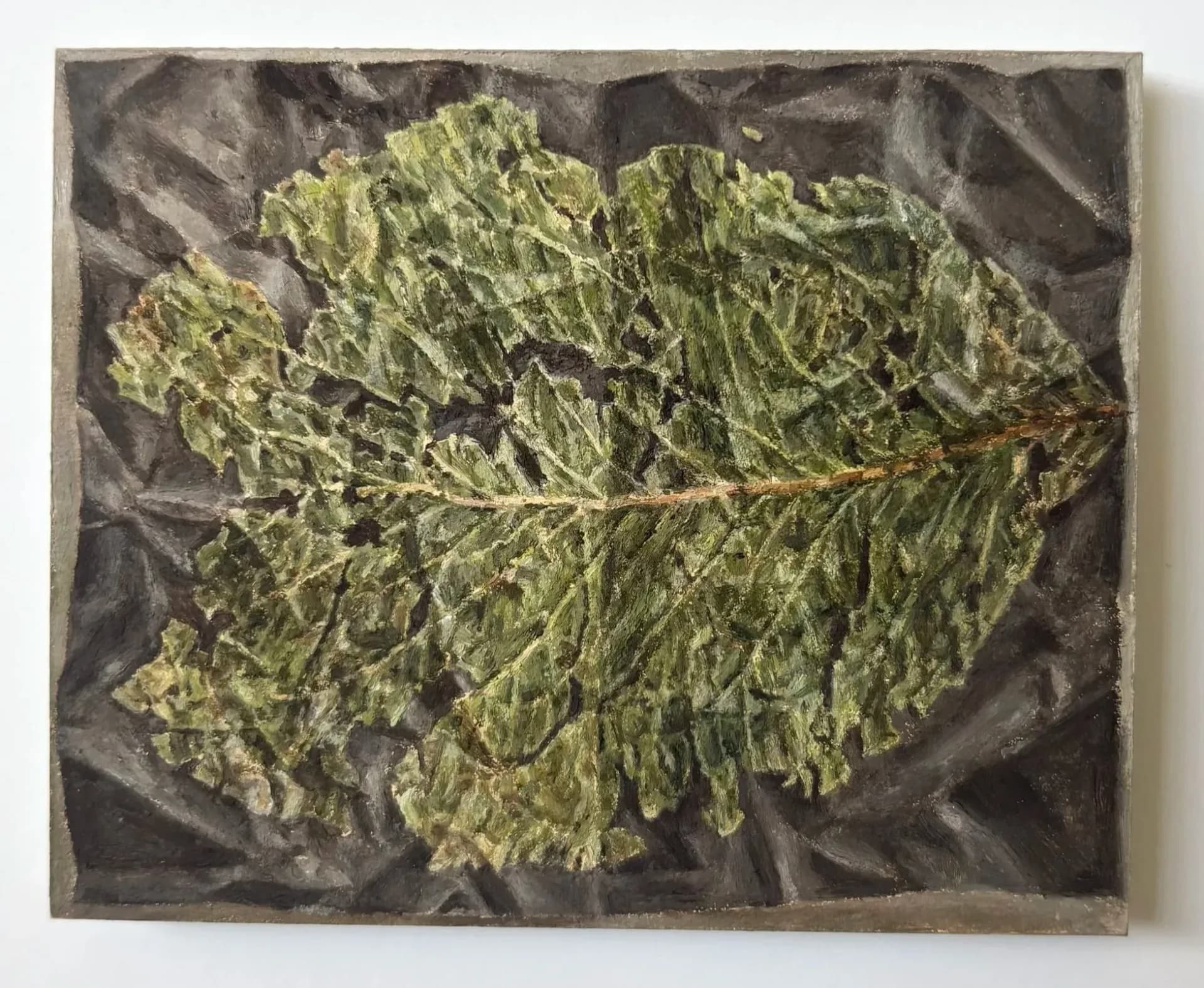 Yellow-green leaf with detailed vein texture displayed on dark fabric backing, mixed-media composition.
