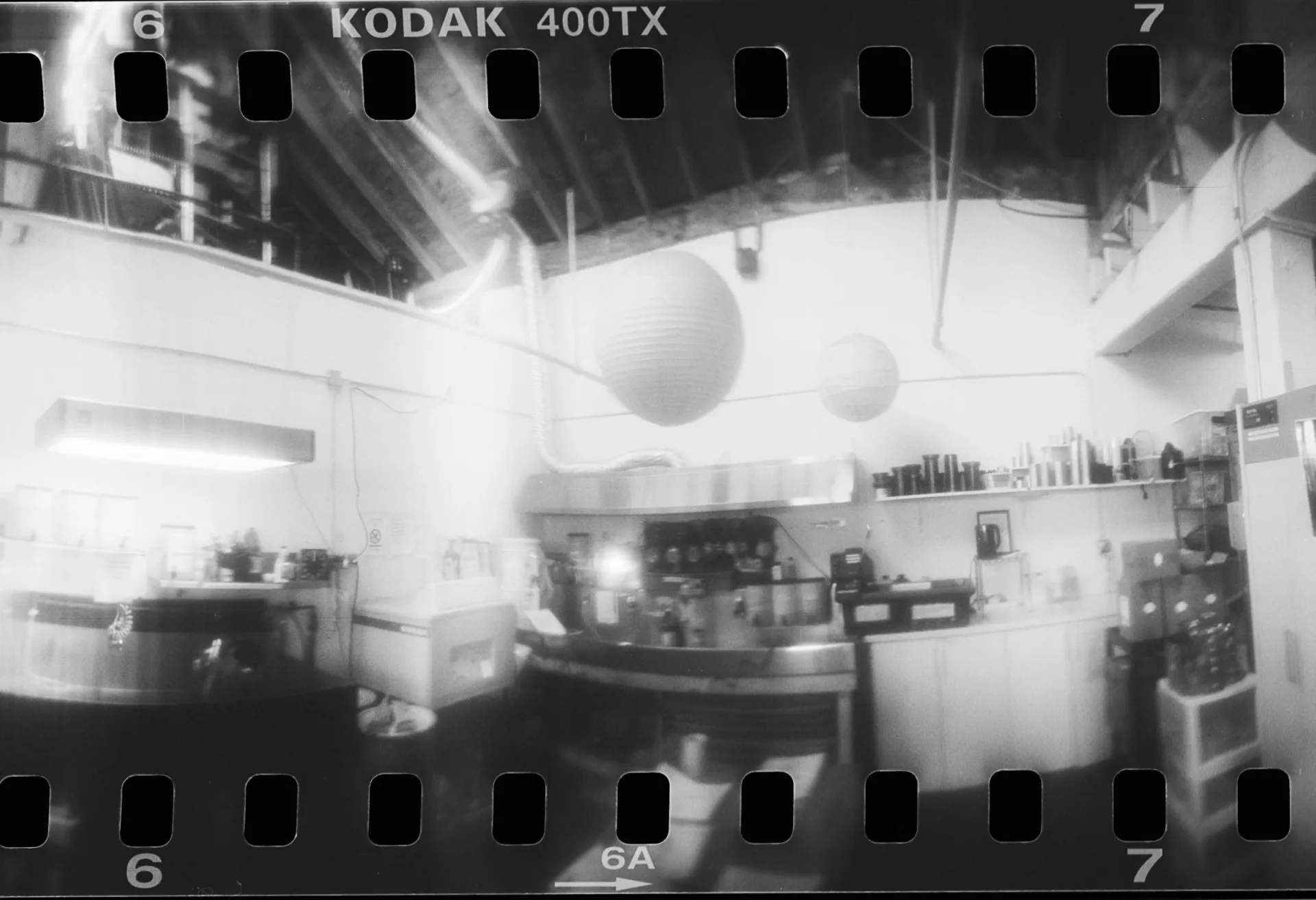 Black and white film strip photograph labeled Kodak 400TX showing an interior studio or workspace with hanging spheres and darkroom equipment.