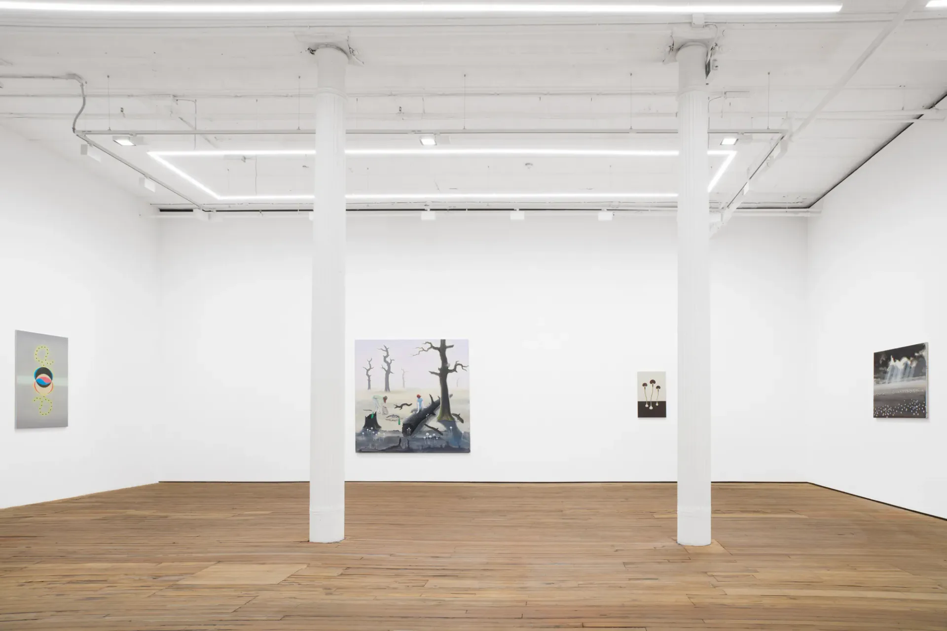 Minimalist gallery interior with white walls, wooden floors, support columns, and several artworks spaced across the walls including a ship-themed painting.