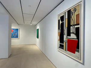 Gallery hallway with white walls, framed abstract artworks in vivid colors, green vertical element, and clean minimalist aesthetic.