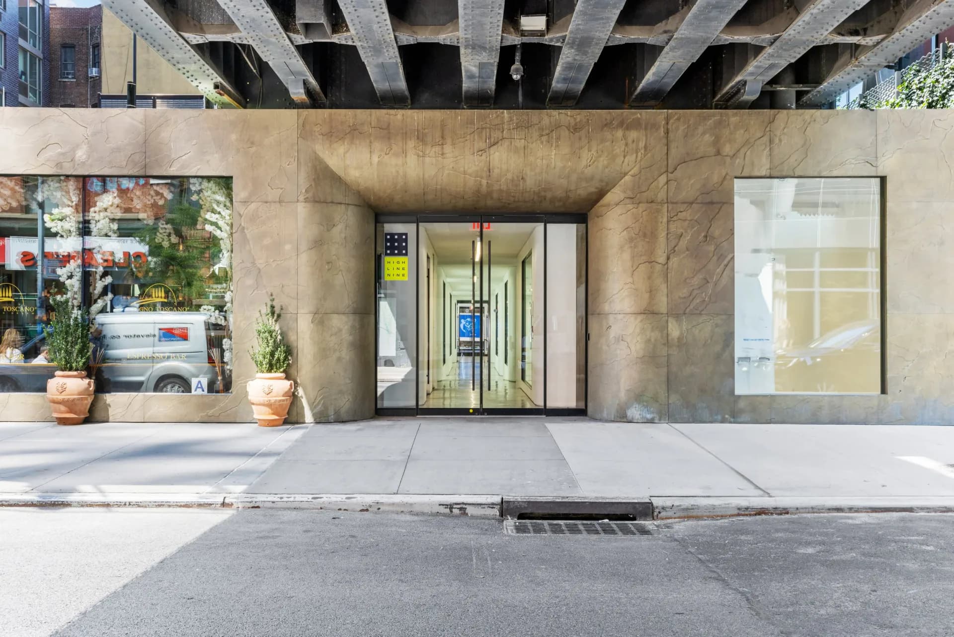 High Line Nine Galleries storefront facade with concrete brutalist architecture, large window displays with potted plants, and reflective glass entrance doors at street level.
