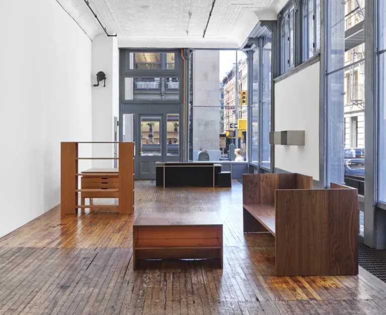 Judd Foundation gallery interior with wooden furniture pieces and large windows overlooking a city street.