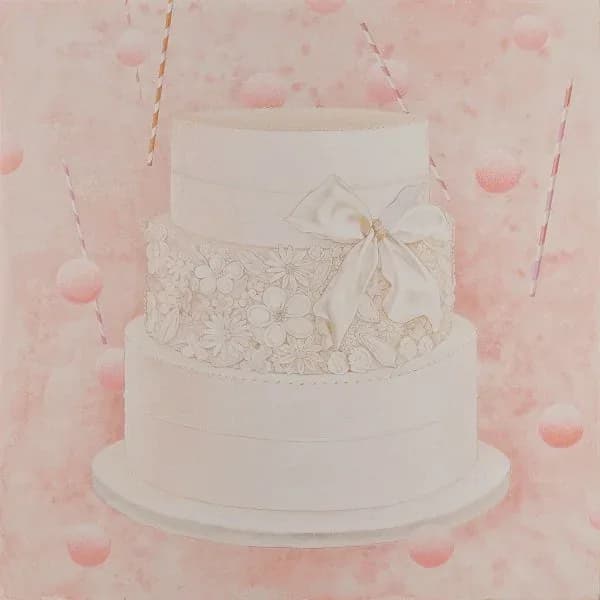 Three-tier white wedding cake with lace detail and cream ribbon bow, surrounded by pink confetti and striped straws.