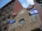 Blurred close-up view of building exterior with Israeli flags hanging from the synagogue.