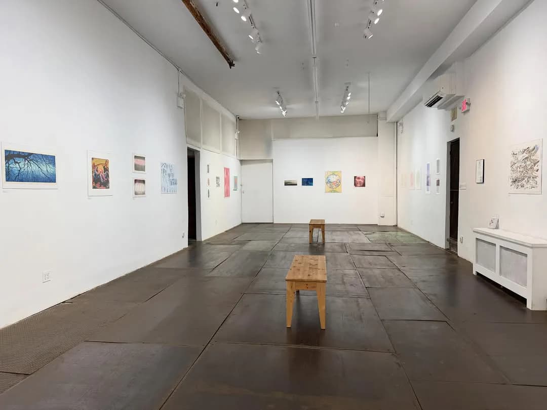 Empty gallery interior at Kentler International Drawing Space with wooden bench, artworks on walls, and dark flooring.