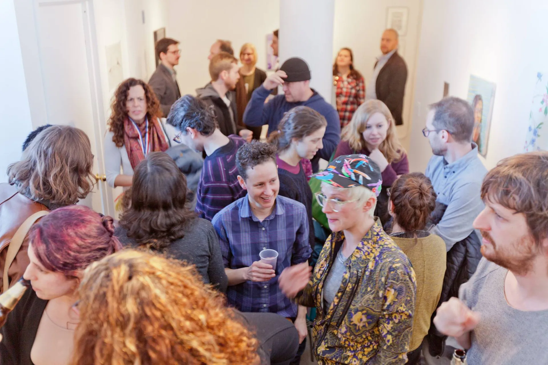 Crowded interior of Kunstraum LLC gallery with visitors conversing in a white-walled space during an opening or event.