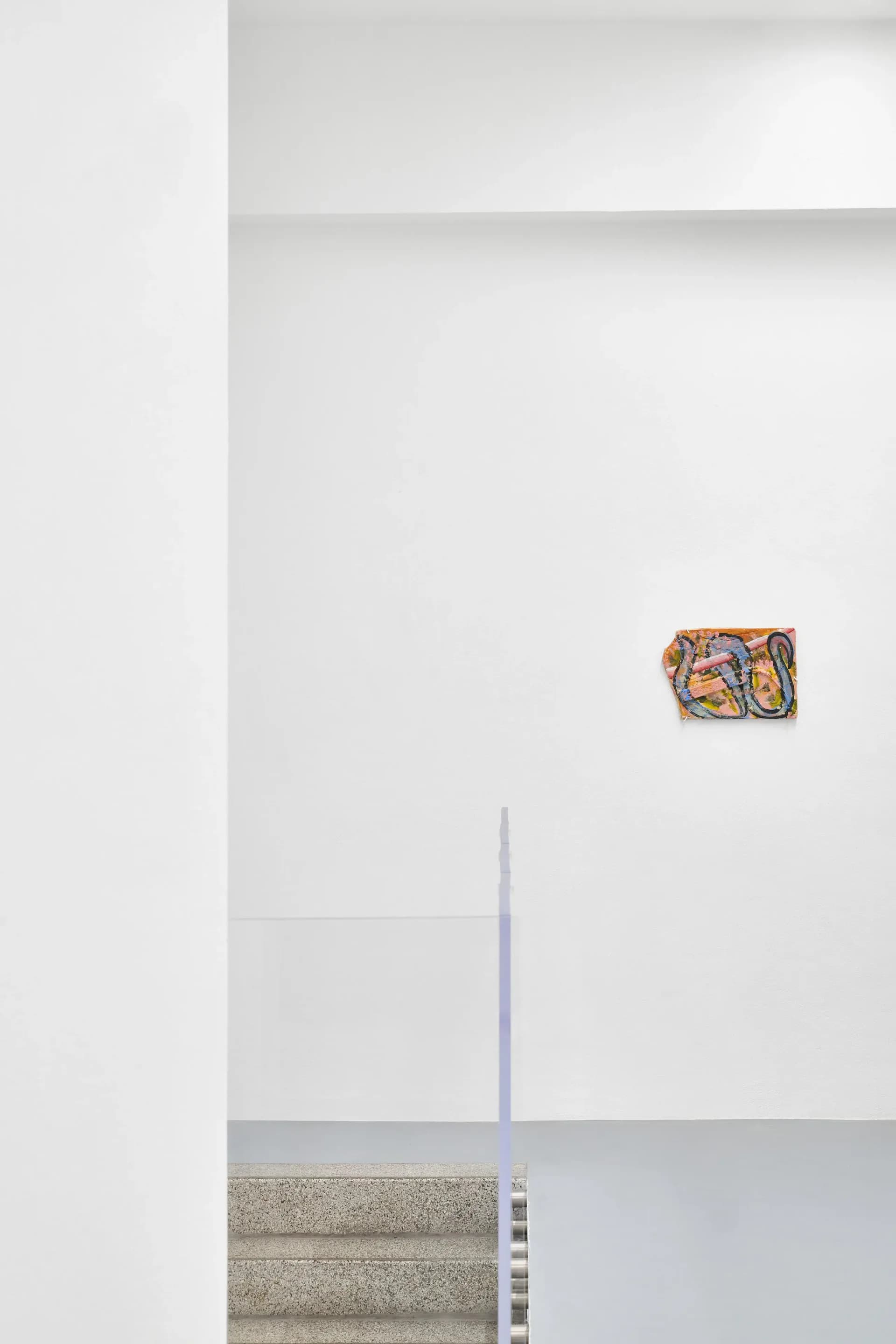 Minimalist gallery wall with small colorful abstract artwork mounted high, textured concrete baseboard, and architectural elements in neutral tones.