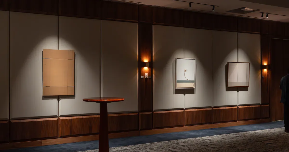 Leon Tovar Gallery interior with illuminated wall-mounted artworks in light boxes, wooden lower panels, and warm ambient lighting.