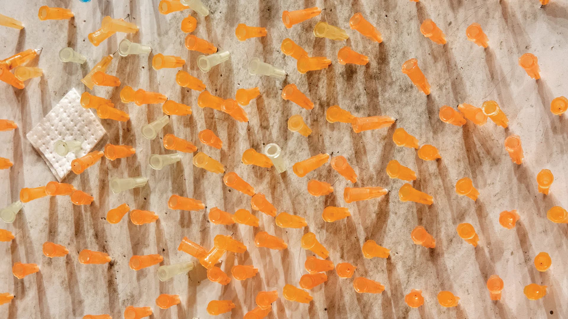 Overhead view of scattered bright orange paper squares on a wooden textured surface with white paper edges.