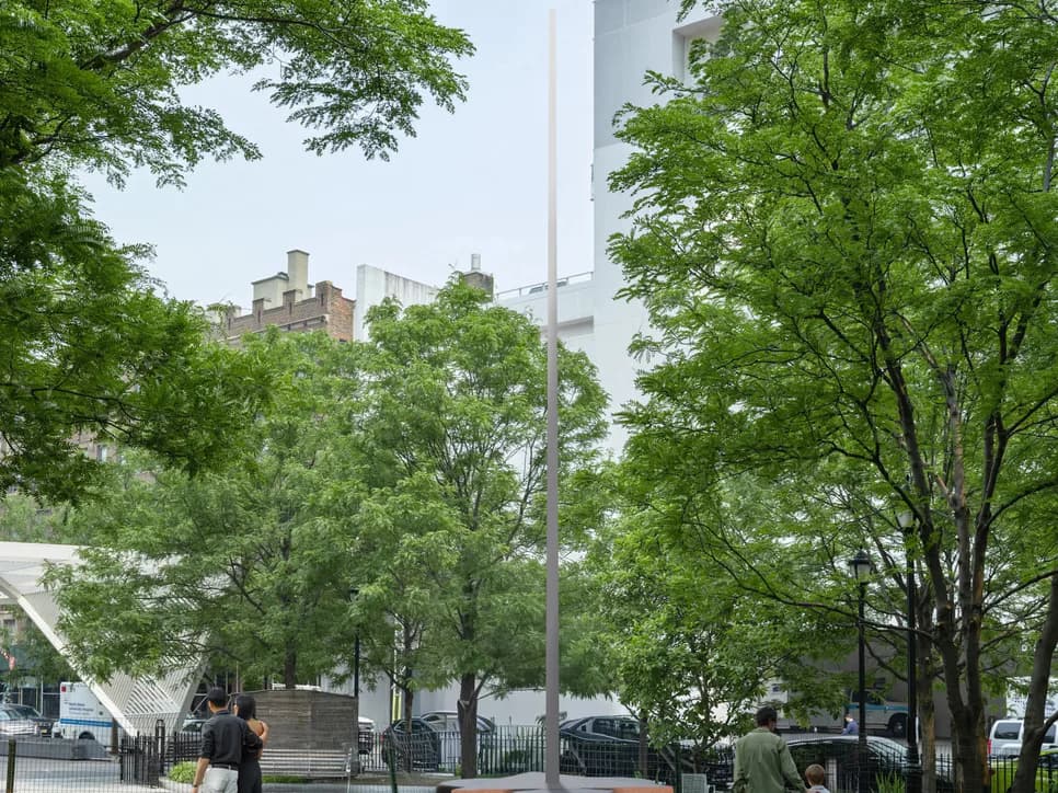 Exterior plaza surrounded by green trees and a tall building structure; street-level urban gallery location.