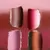 Minimalist composition of three vertical cylindrical forms in shades of red and pink against a neutral background.
