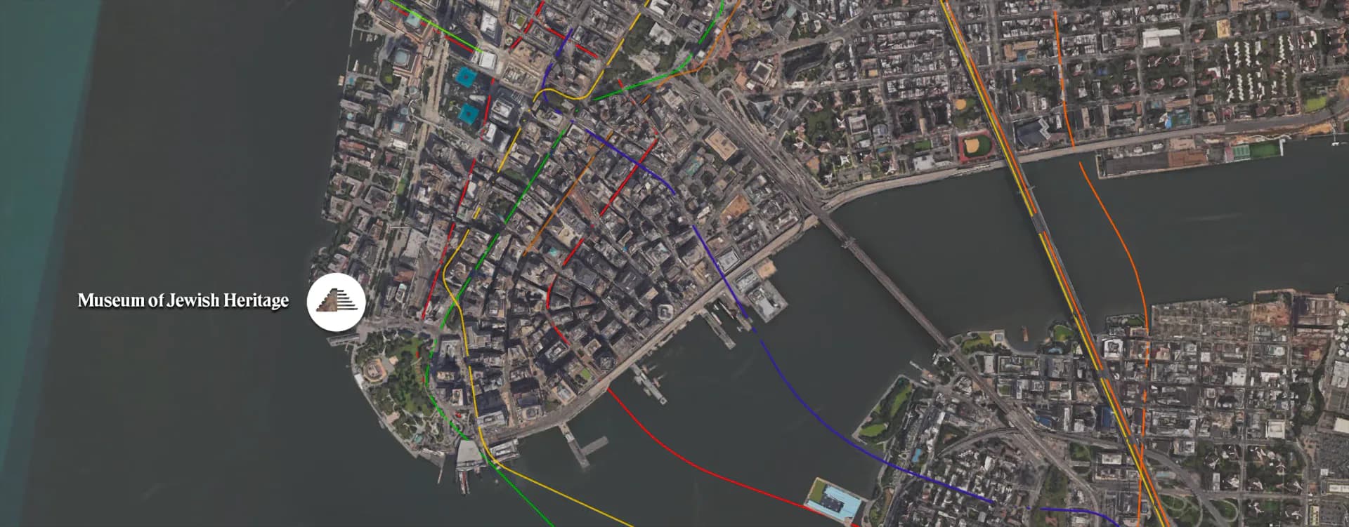 Aerial satellite map showing waterfront district with 'Monument Jewish Heritage' location marker indicated on left side.