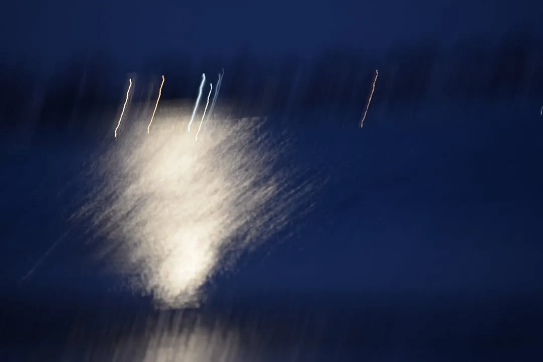Abstract artwork with dark blue background and a bright white central burst or explosion with radiating lines, suggesting movement or energy.