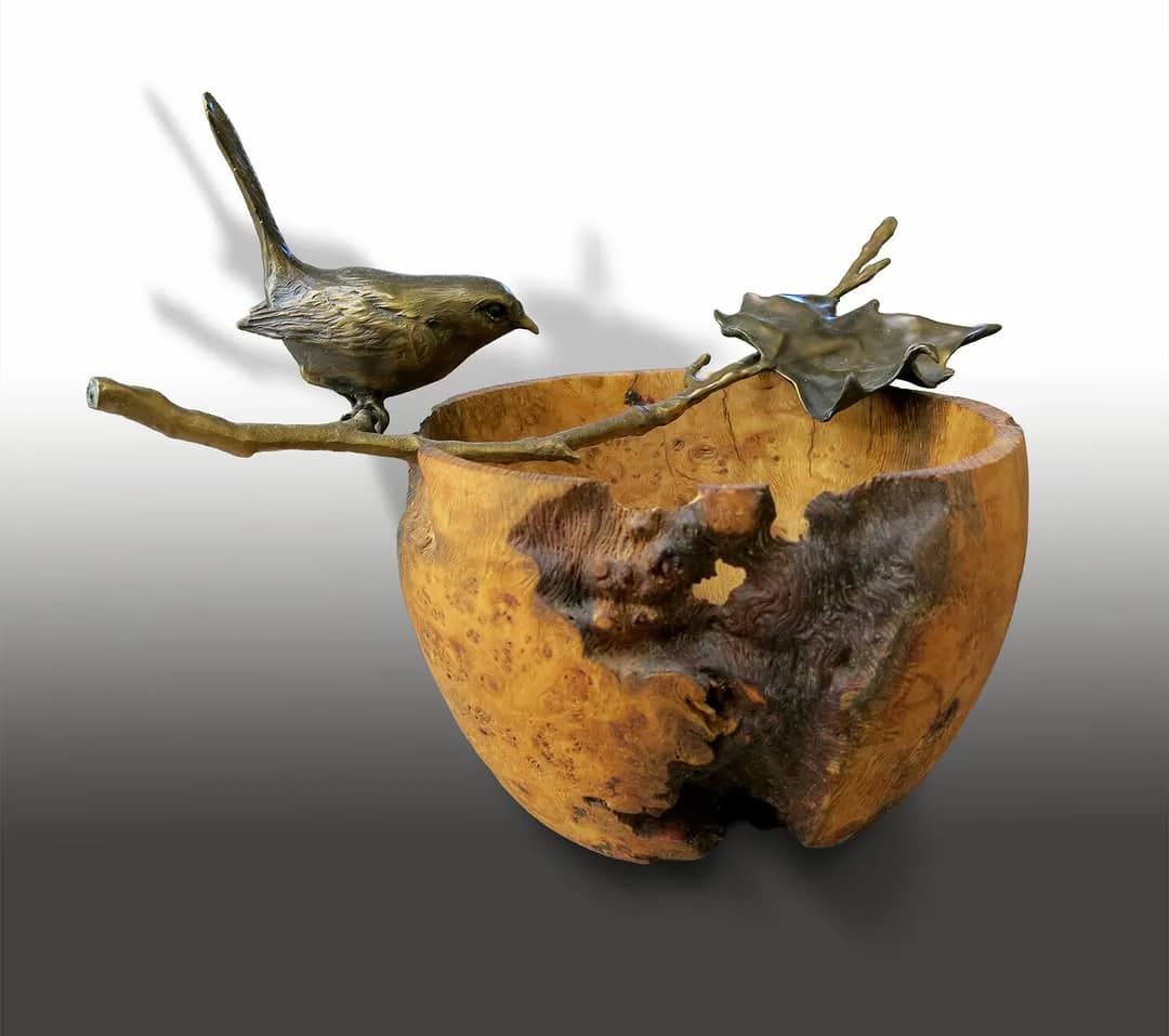 Mixed-media sculptural artwork featuring a golden-brown apple form with two bronze bird figures perched on branches, showing texture and patina.