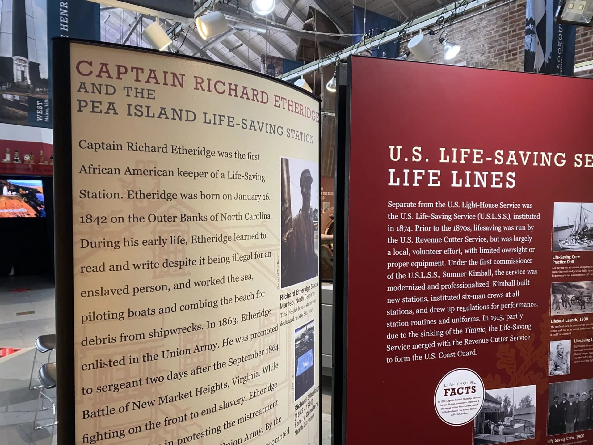 Interior museum display at National Lighthouse Museum showing two informational panels about Captain Richard Etheridge and U.S. Life-Saving Service, with brick walls and mounted exhibits.