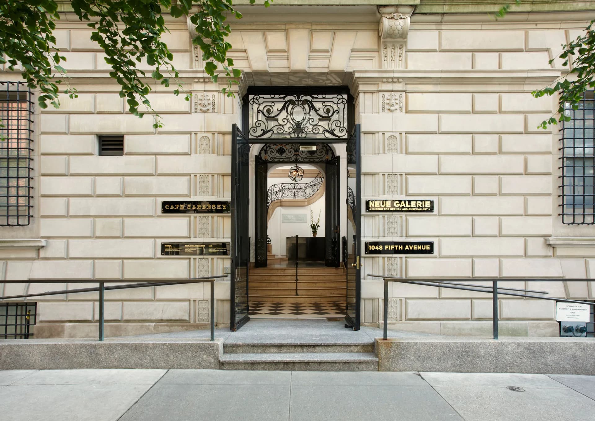 Gallery storefront entrance on a Manhattan street, featuring a black ornate door frame set within a classical stone facade with shop signage above.