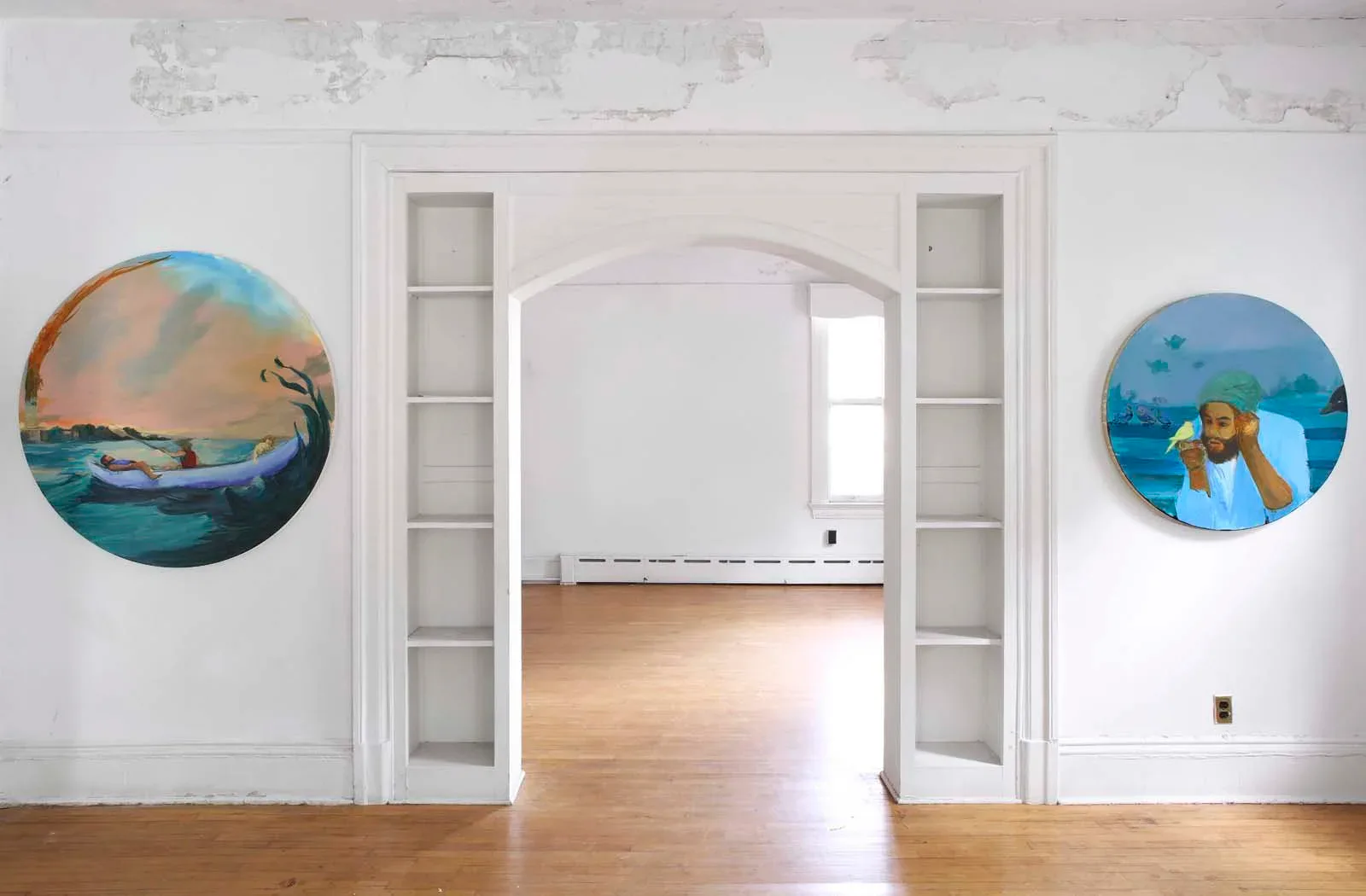 Gallery hallway with white walls, arched doorway, and two circular paintings on either side featuring water scenes and figures in warm and cool color palettes.