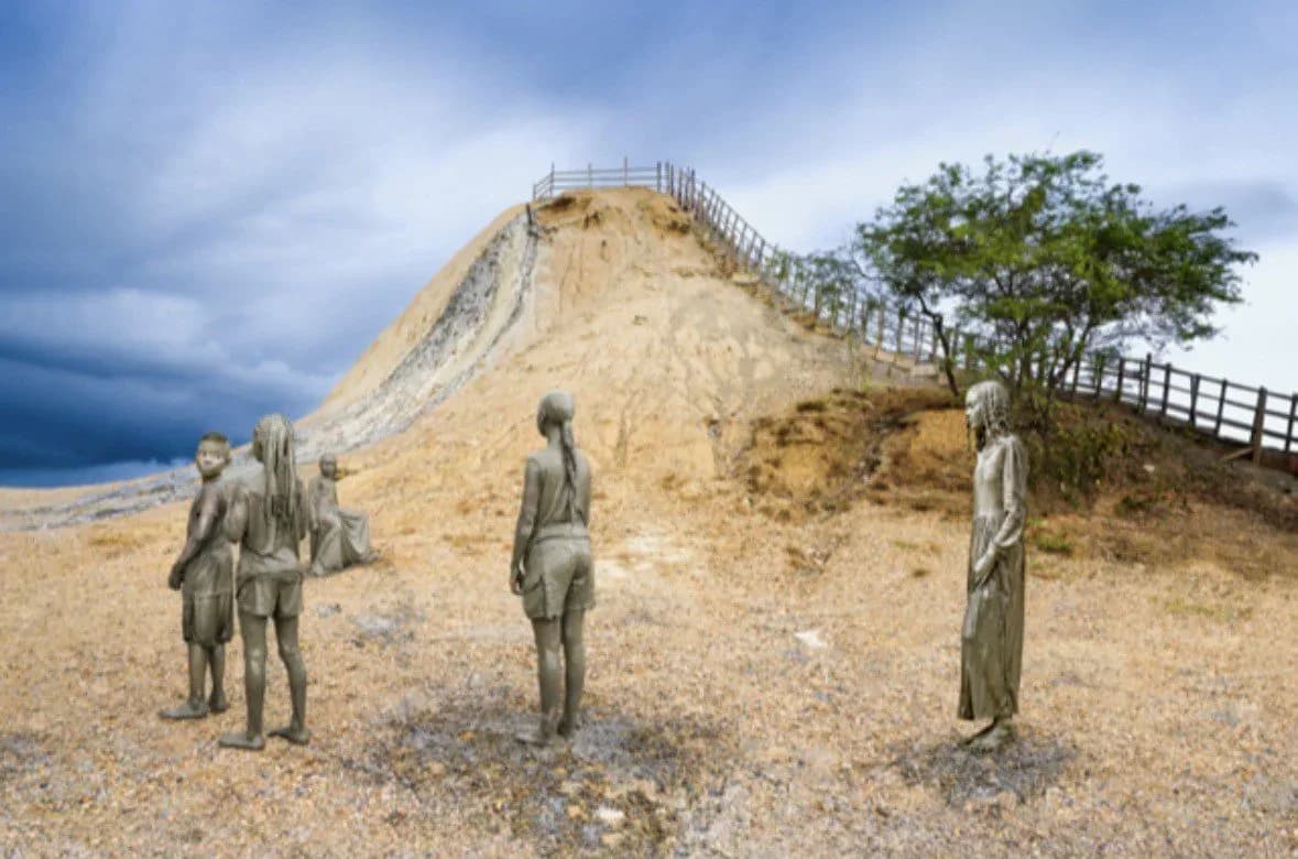 Three cast bronze human figures standing in a desert landscape at the base of a large conical mound with viewing platform and railings.