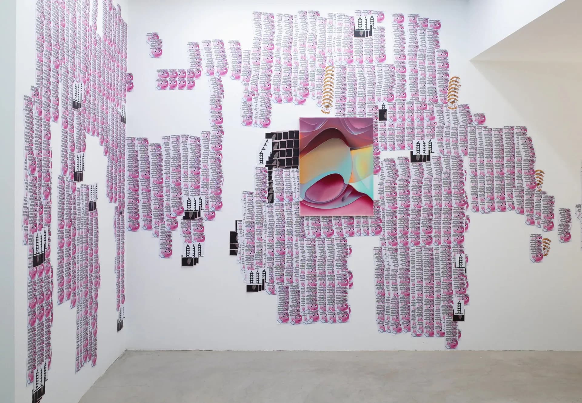 Gallery wall densely installed with pink cylindrical objects and hanging elements surrounding a central colorful abstract textile or paper work.