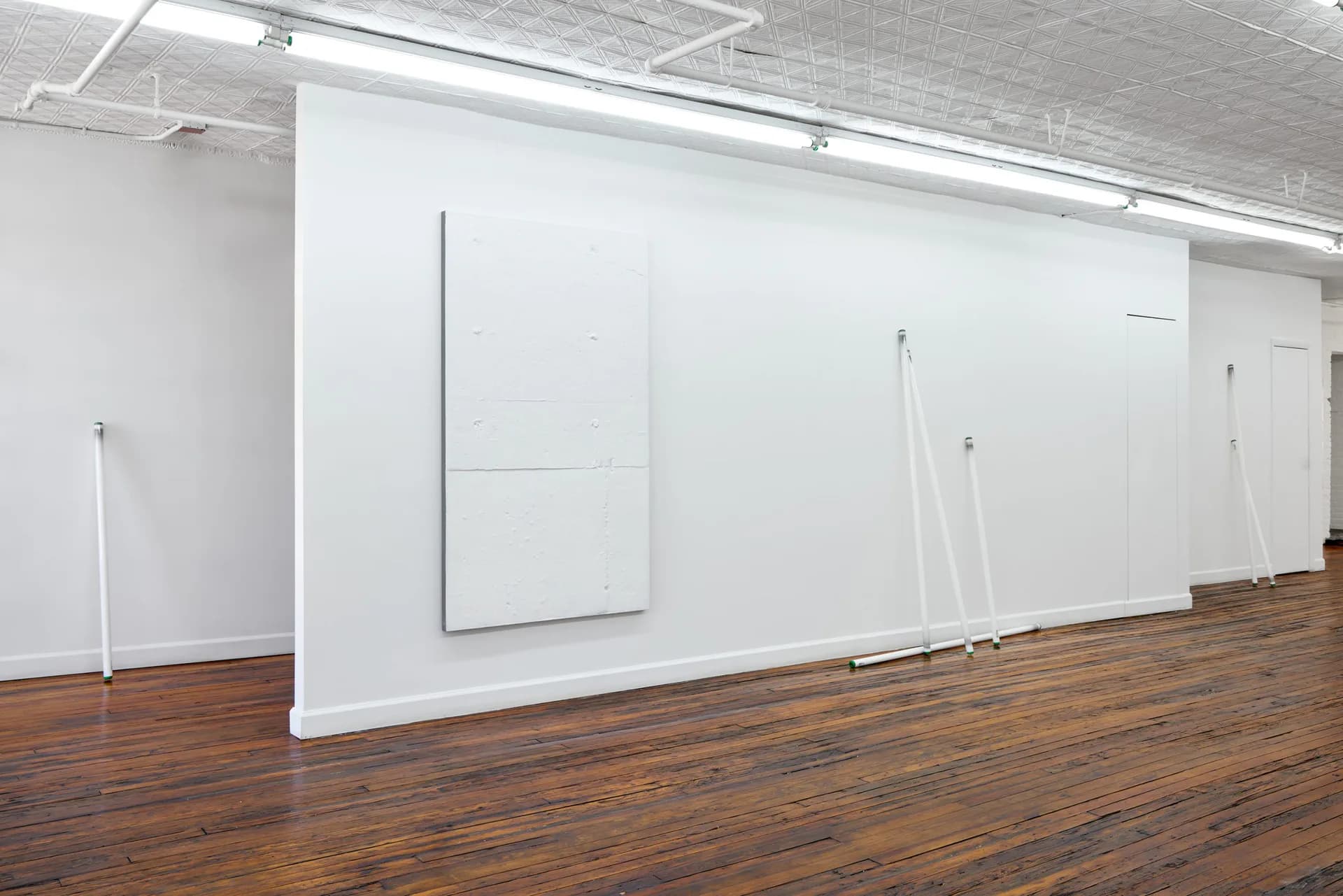 Off Paradise gallery interior with white wall panels, wooden floor, and track lighting in a minimalist exhibition space.