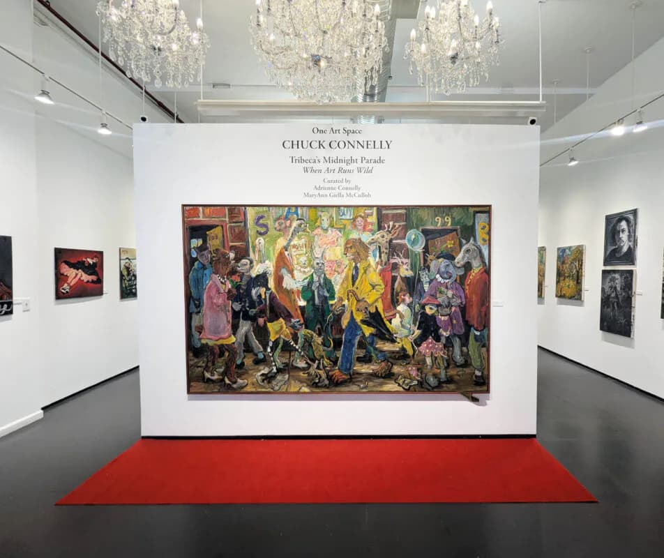 Interior gallery view with white walls, crystal chandeliers, red carpet runner, and colorful figurative paintings displayed, including a large central work by Chuck Connelly.