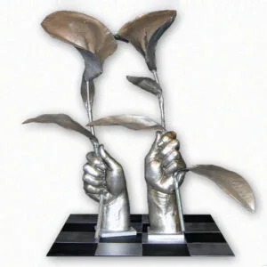 Sculptural artwork: two silver-metallic hands emerging from black base platform, grasping or holding stylized leaf forms in muted green and brown tones.