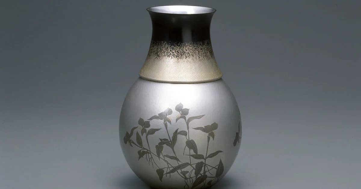 White ceramic vessel with metallic top, decorated with etched botanical motifs and delicate plant imagery.
