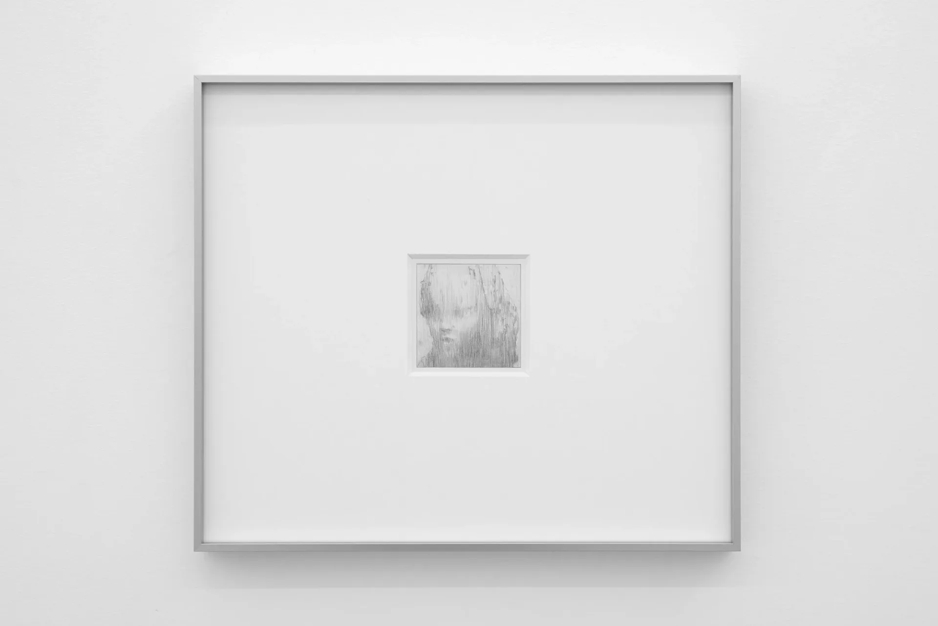 Gallery wall with gray frame displaying a small framed portrait or figure artwork centered on white matting.