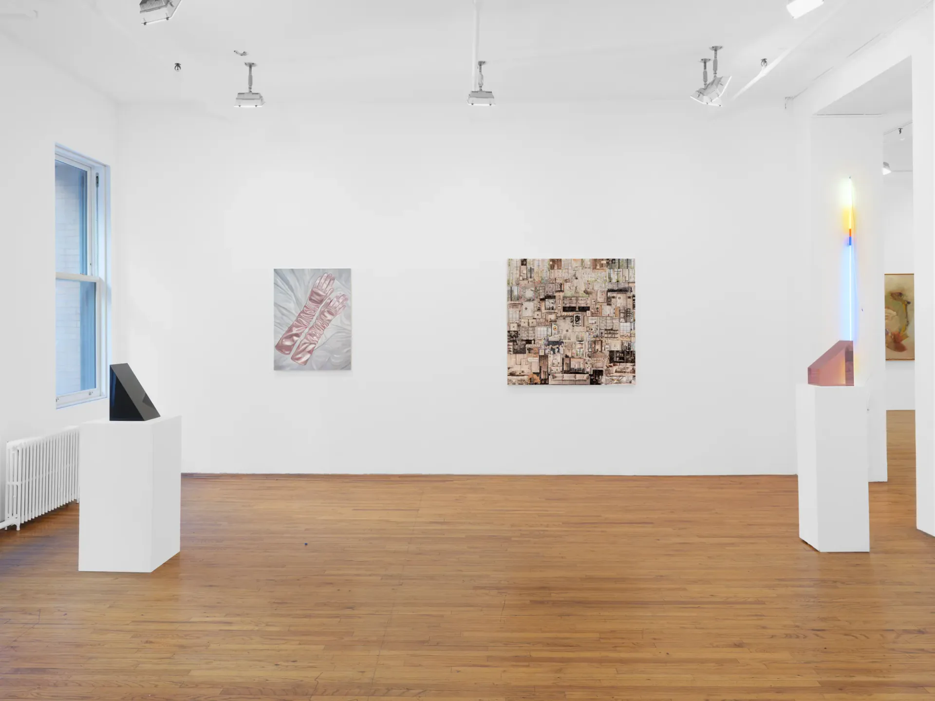 Minimalist gallery interior with wooden floor, white partition walls, framed mixed-media artworks on walls, neon light installation, and blue window.