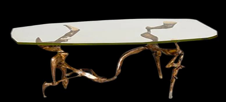 Contemporary glass-top dining table with bronze sculptural human figure base supporting the surface.