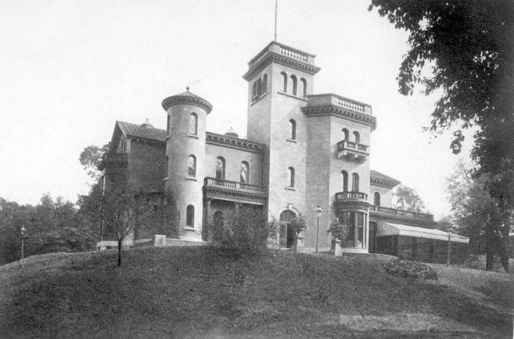 Black and white historical photograph of a stone castle-like building with towers situated on a rise in Prospect Park.