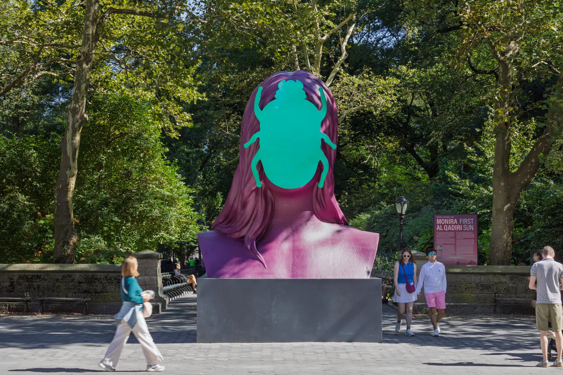 Large public sculpture bust with magenta hair and turquoise face against tree-lined plaza, presented by Public Art Fund in New York.