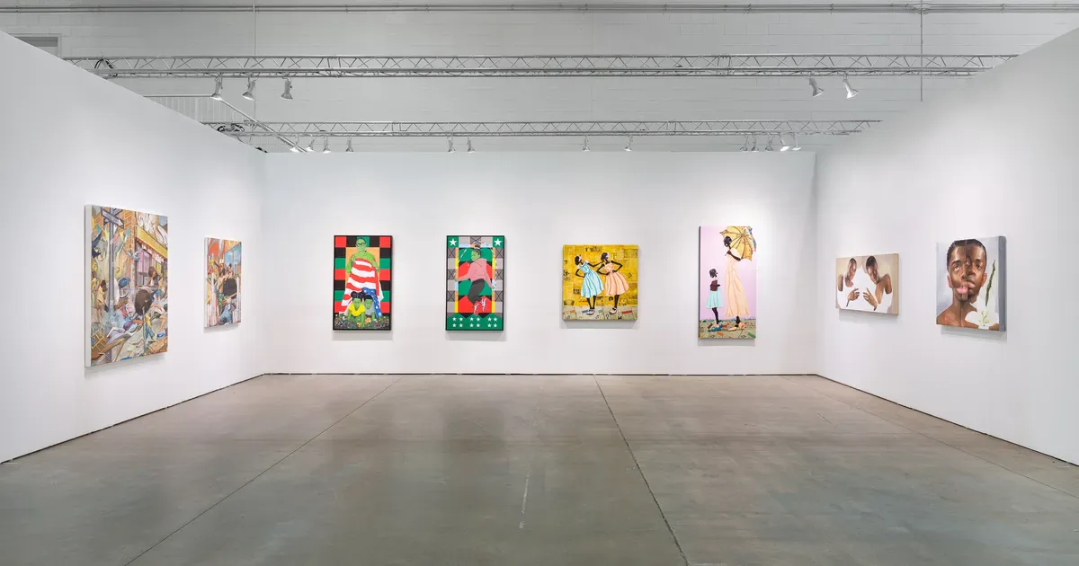 Gallery interior at Richard Beavers Gallery with white walls, gray polished concrete floor, and eight colorful artworks displayed on the back wall under track lighting.