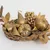 Abstract sculptural form with organic, tangled golden-brown fibrous or mesh-like materials creating a dense, textured three-dimensional composition.