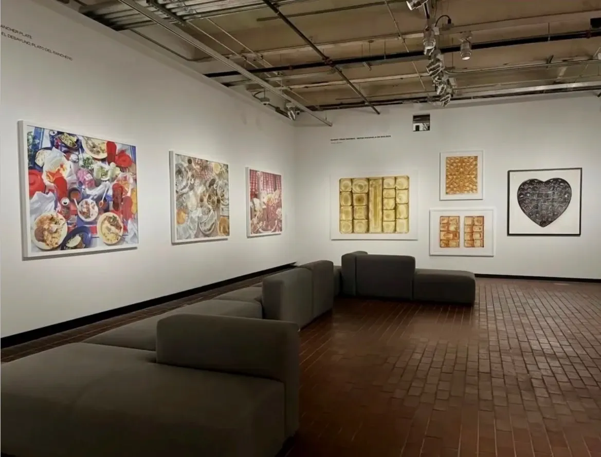 Gallery interior with curved seating and multiple framed artworks on white walls, including colorful and abstract pieces.