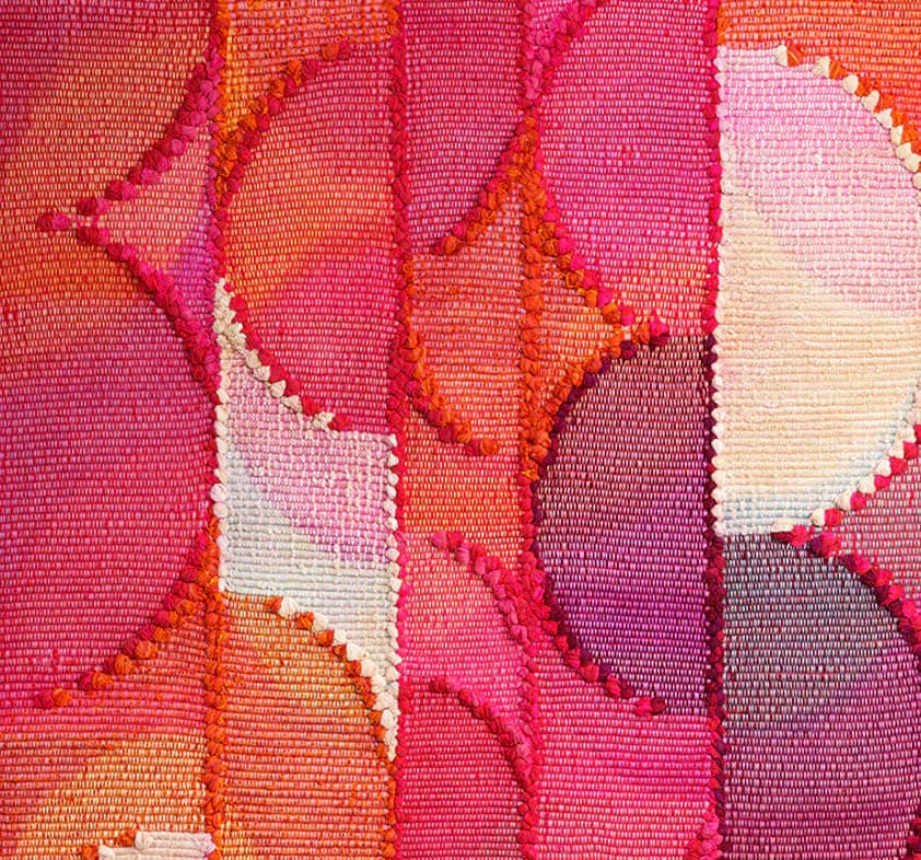 Woven textile with vibrant pink, orange, and purple tones featuring abstract organic shapes and patterns with contrasting white areas, showing detailed fiber texture.