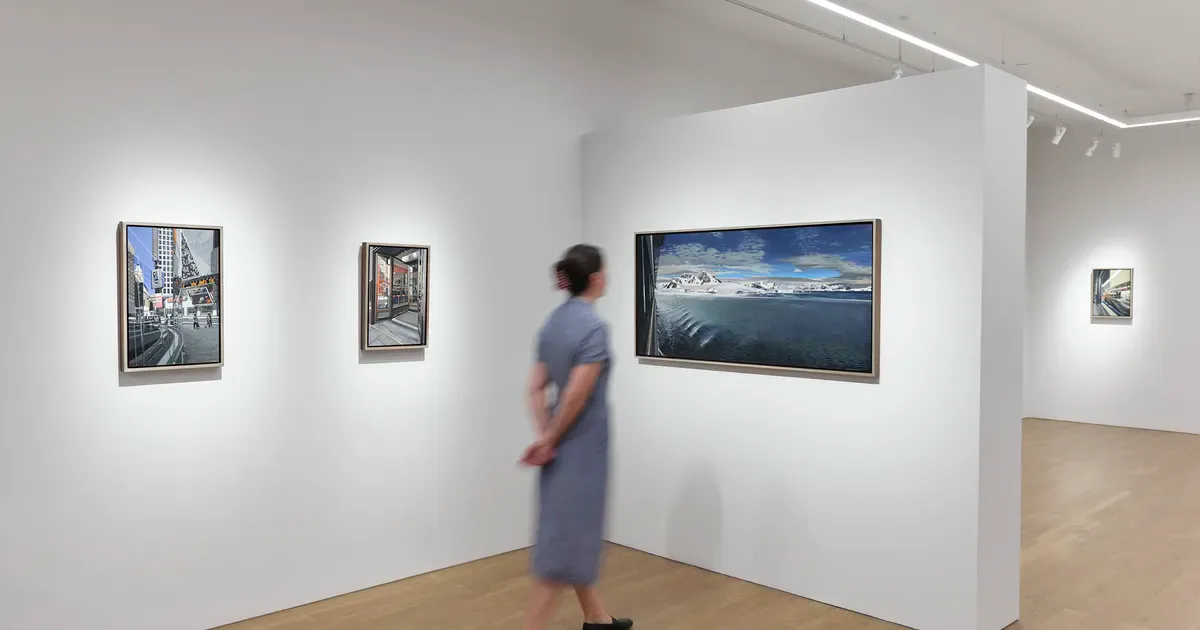 Schoelkopf Gallery interior with white walls displaying framed photographs and a visitor viewing artwork.