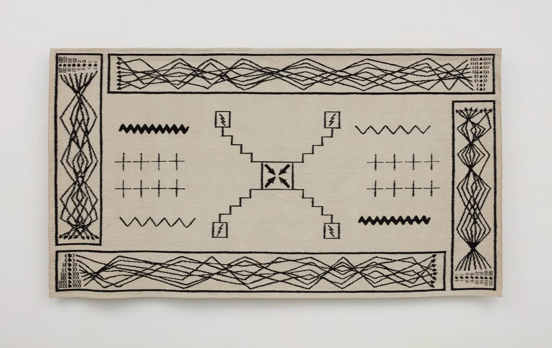 Beige textile or fiber artwork with geometric patterns in black lines—borders, cross-hatching, zigzags, and abstract linear designs arranged symmetrically.