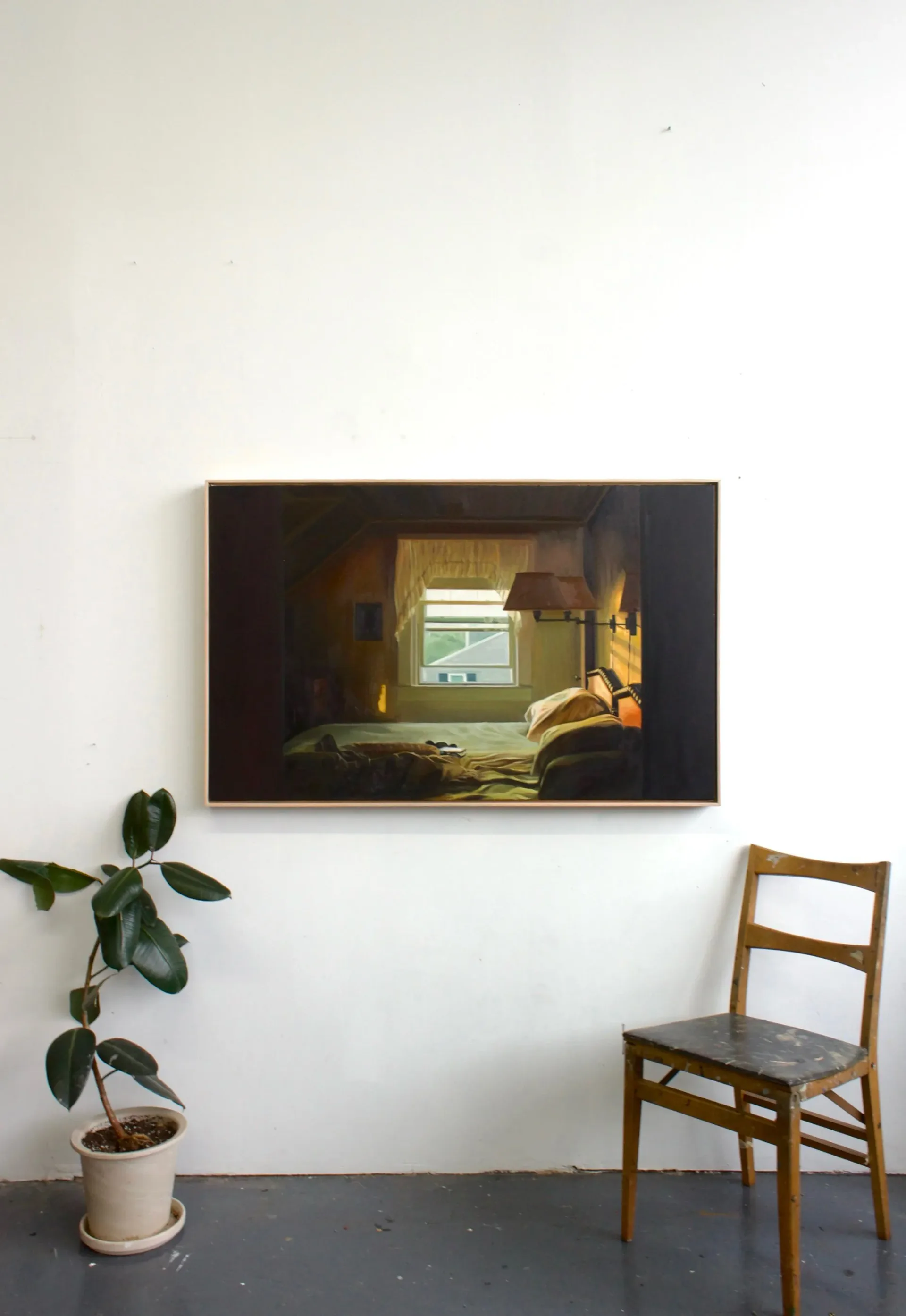 Studio 310 gallery corner with framed painting of sunlit window interior, wooden ladder-back chair, and potted plant on concrete floor.