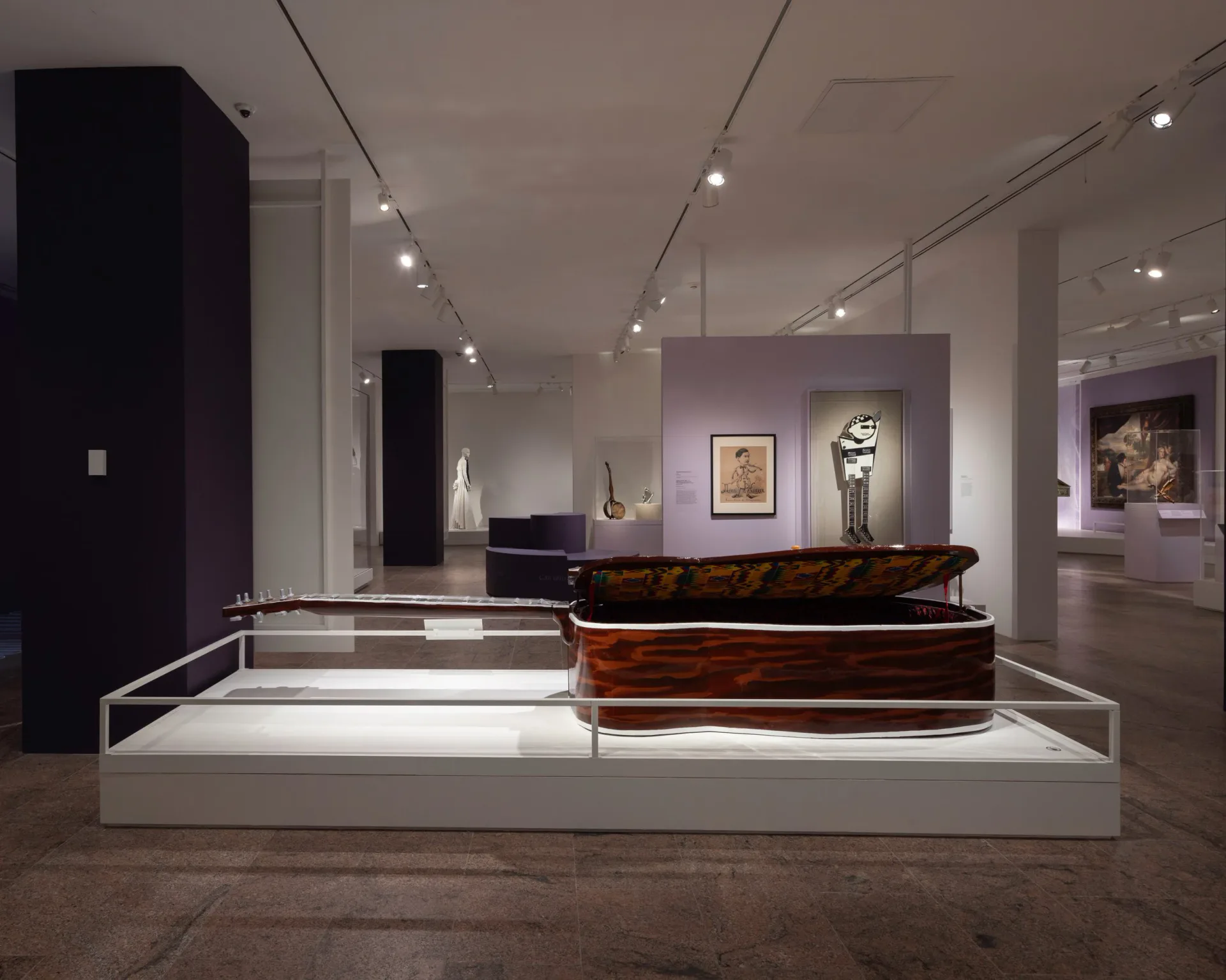 Superhouse gallery interior with white walls, track lighting, purple accent walls, and display cases featuring decorative objects and artwork.