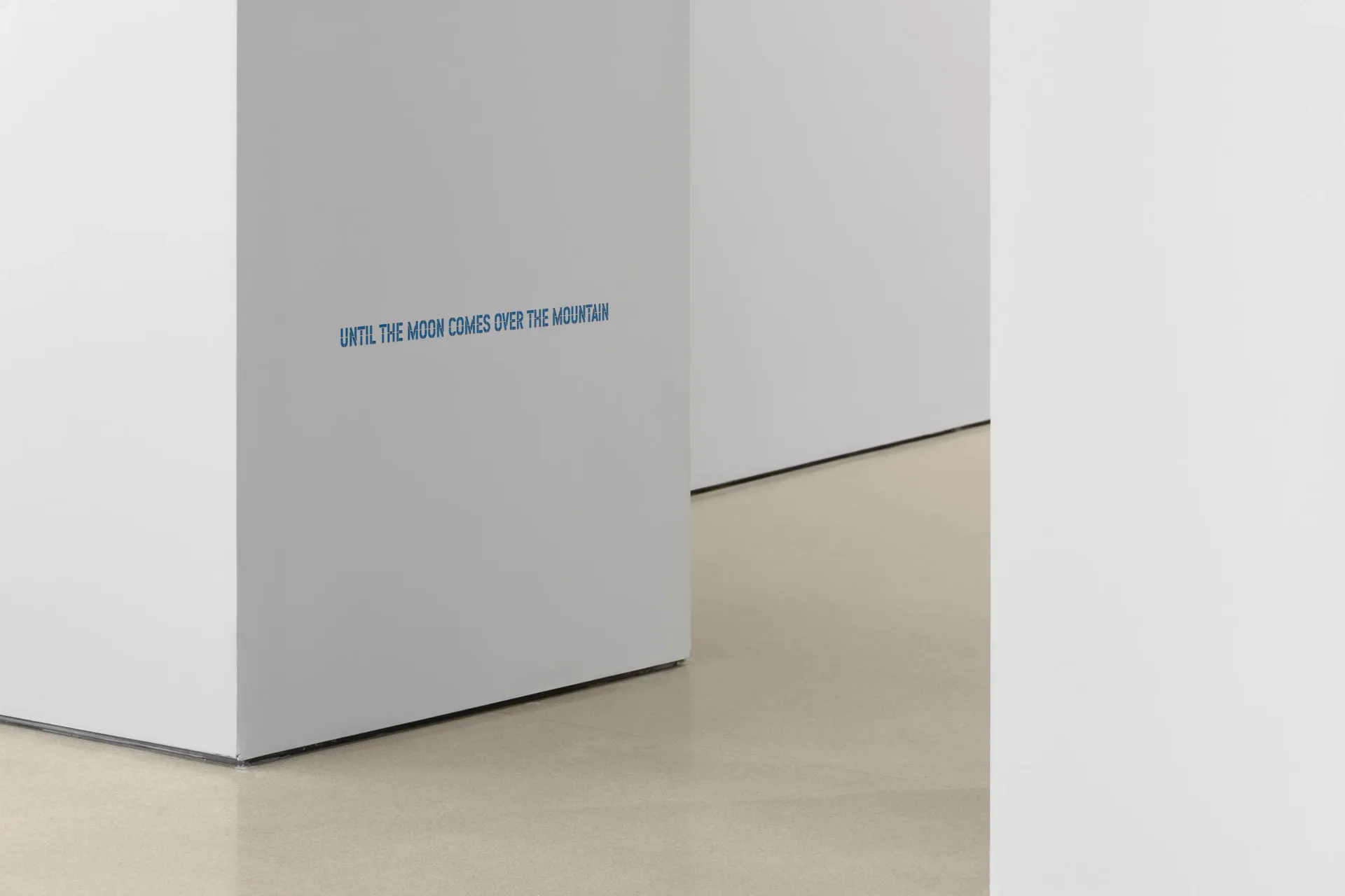White gallery wall corner with blue text reading 'INTO THE NEON CLOUD INTO THE MORPHIA' and minimalist architectural framing.