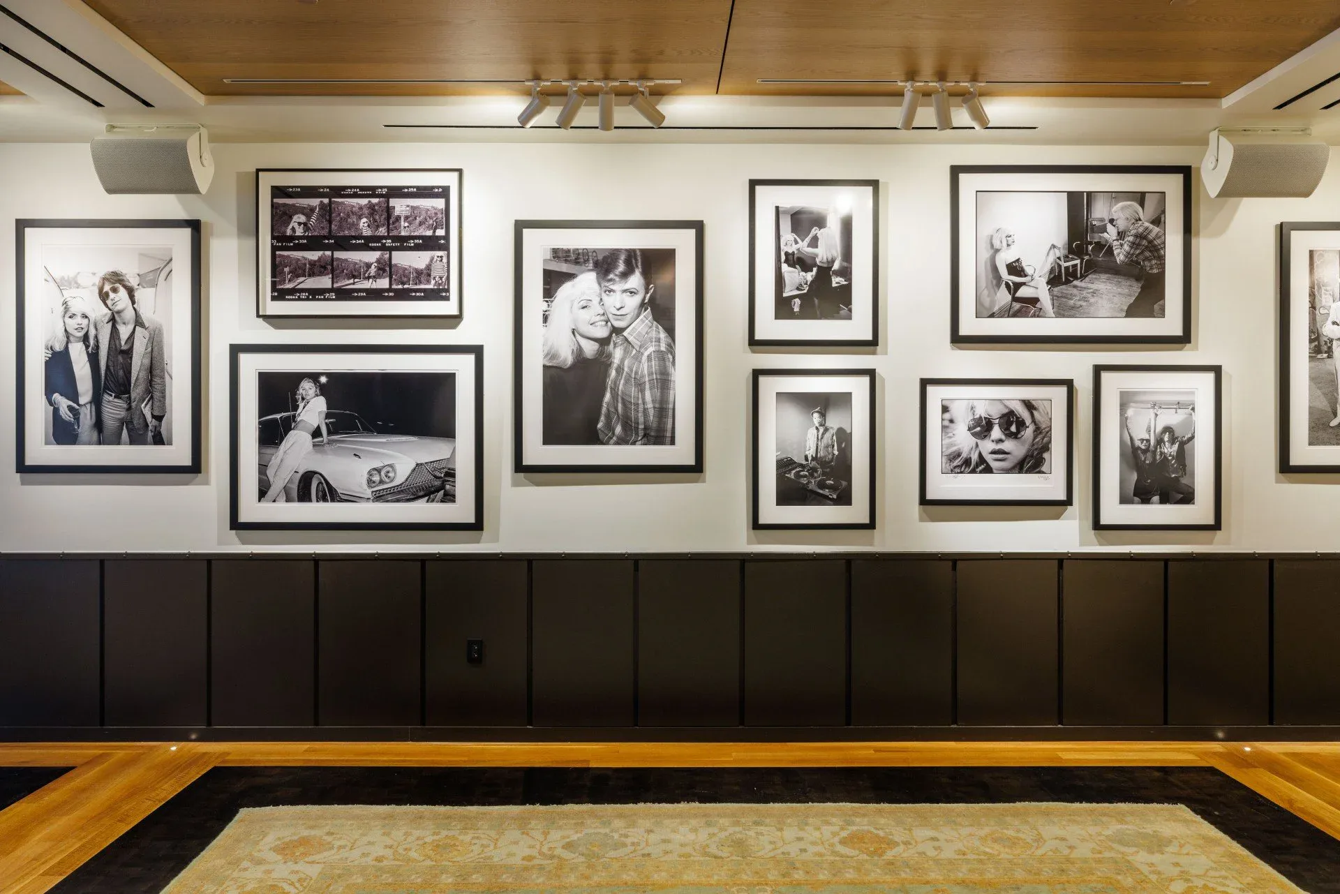 Gallery at Soho Grand interior with black-and-white framed photographs arranged on cream and dark paneled wall, wooden floor visible.