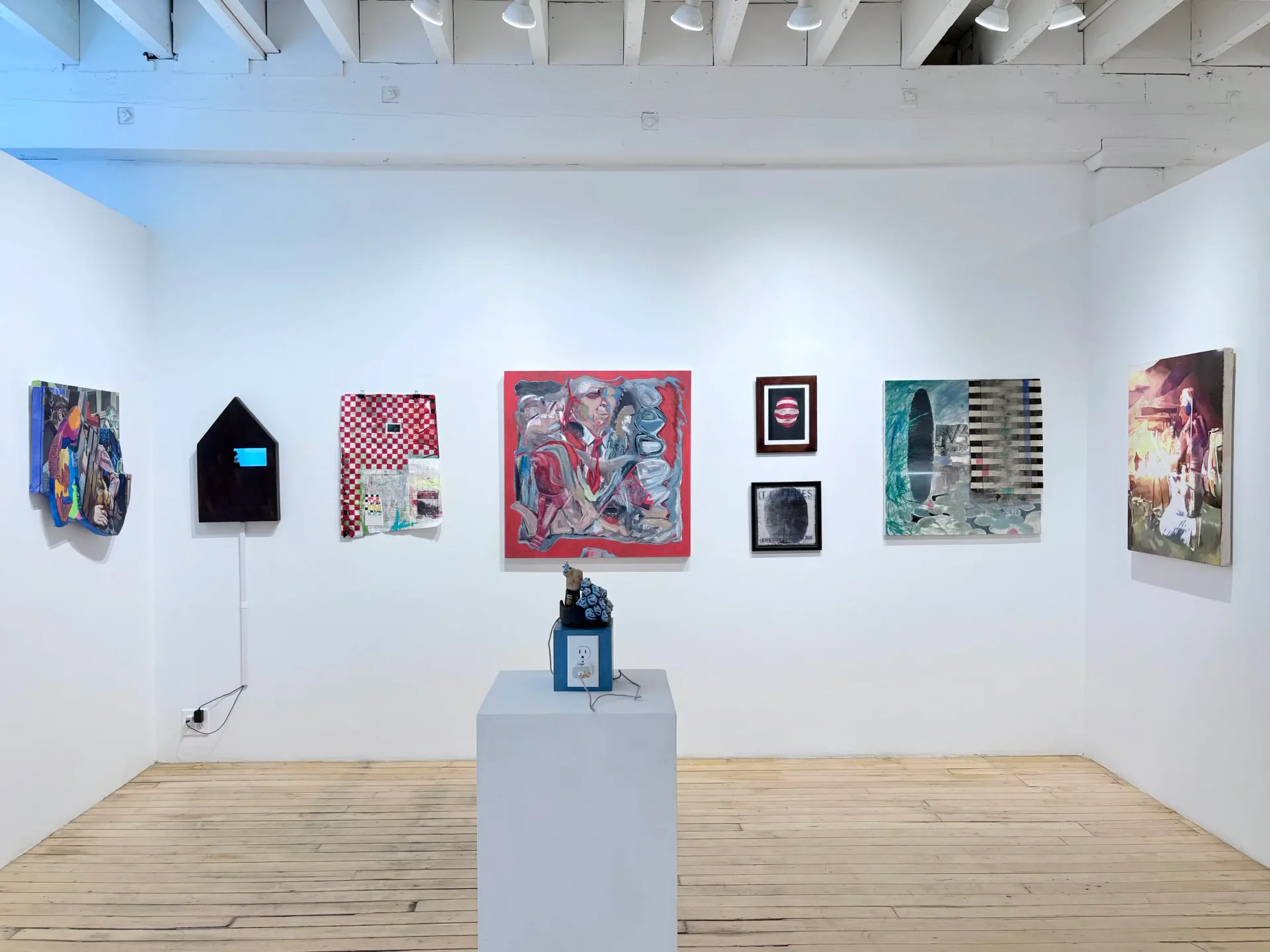 The Painting Center gallery space with light wood floors, white walls, and diverse colorful artworks in various sizes arranged salon-style; white pedestal with sculpture in center.