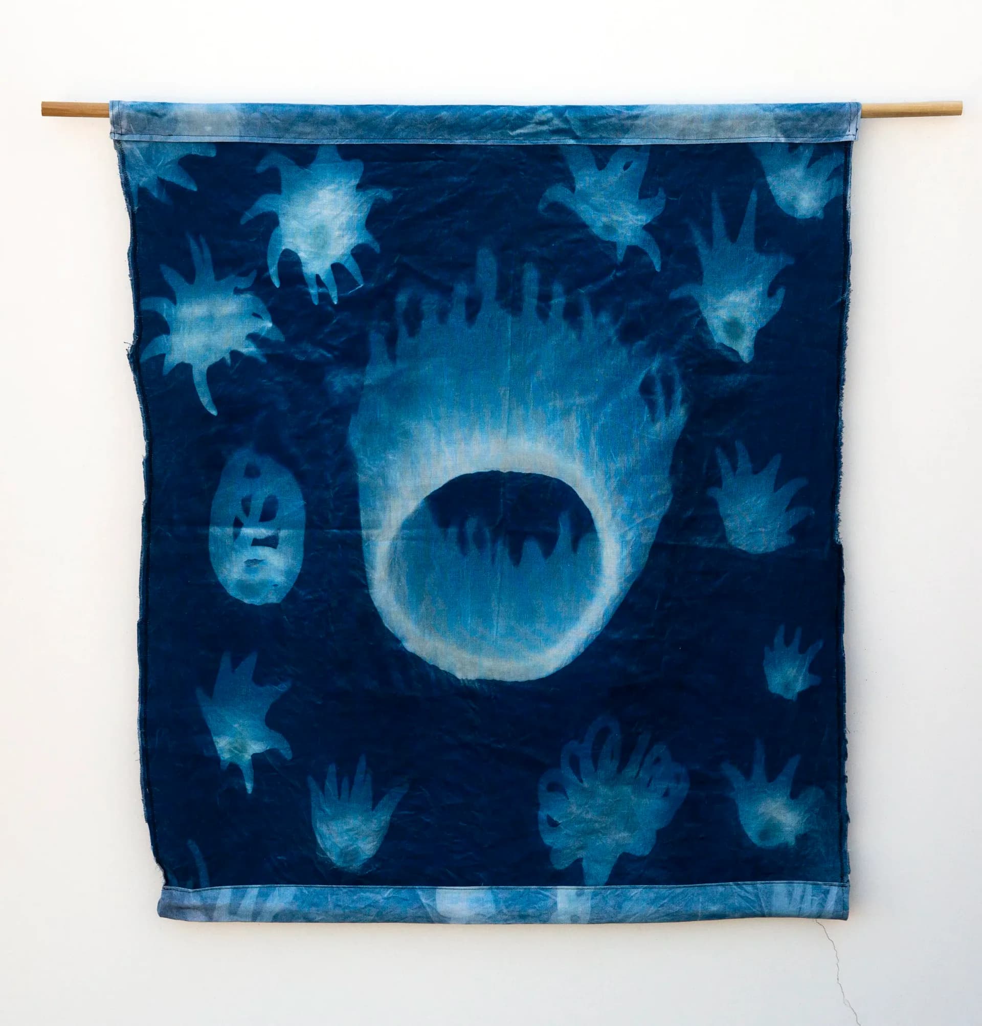 Dark blue textile hanging with cyanotype-style celestial and circular imagery in white and light blue.