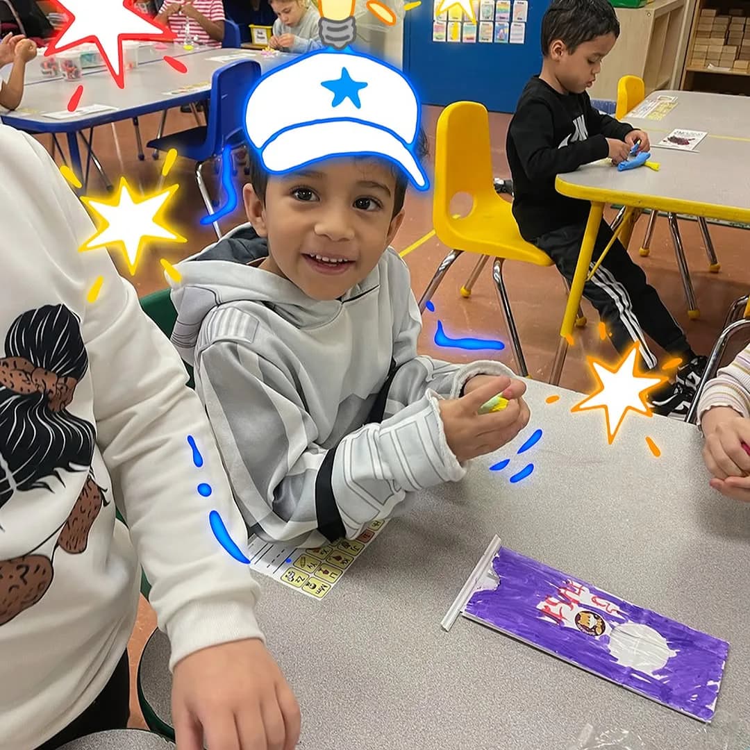 Child wearing star-decorated white captain's hat, smiling at camera during hands-on workshop at Toy Museum of New York, with craft materials visible on table.