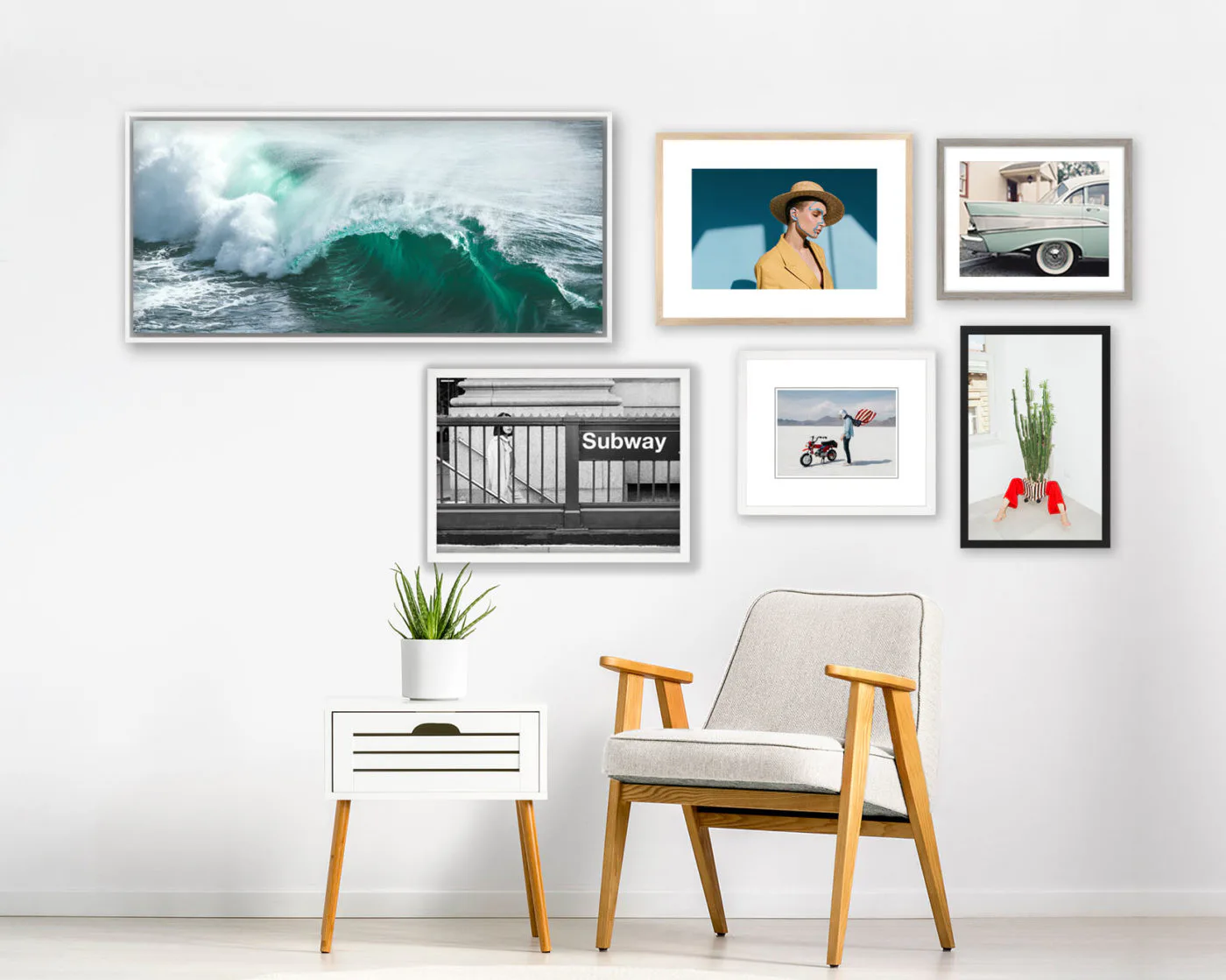 Gallery wall displaying framed photographs and artwork above a mid-century modern chair and white side table with plant.