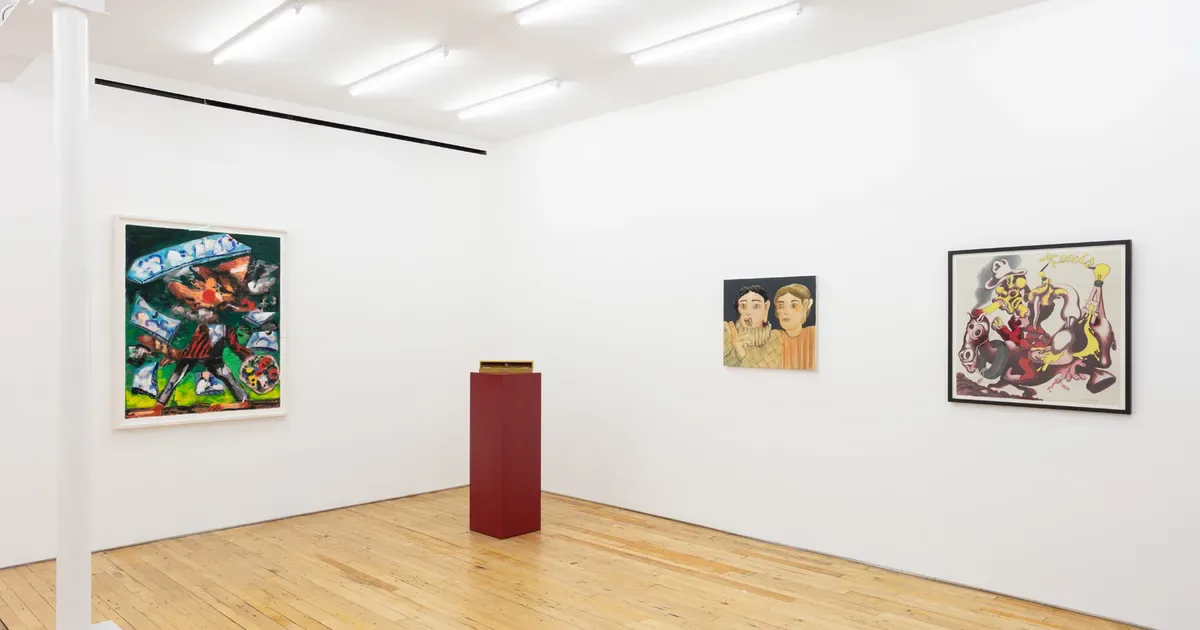 White gallery interior with wooden floor, fluorescent ceiling lights, and three framed artworks on walls; a burgundy cylindrical sculpture stands in center.