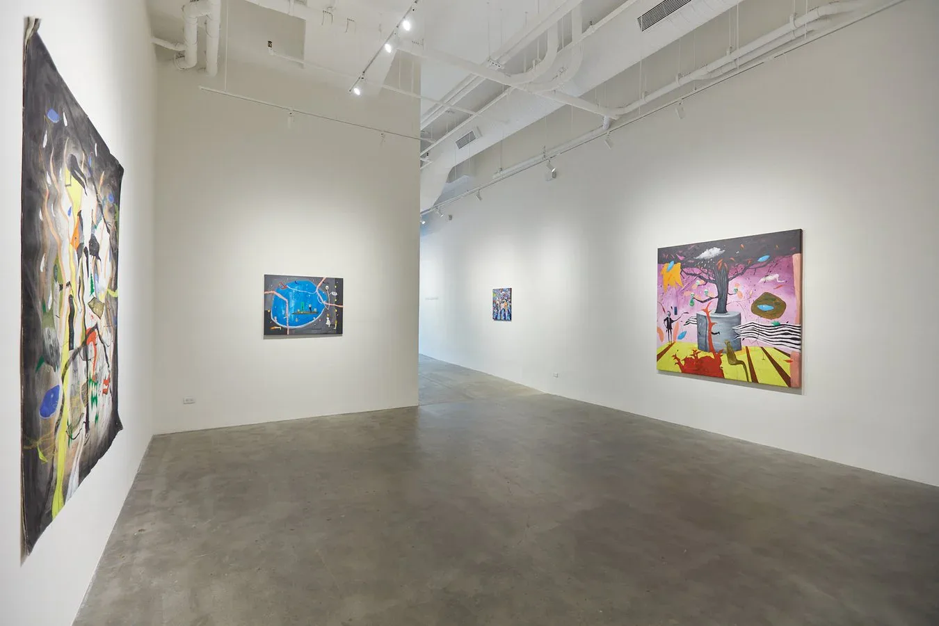 Bright white gallery interior with polished concrete floor and three colorful paintings hung on white walls under track lighting.