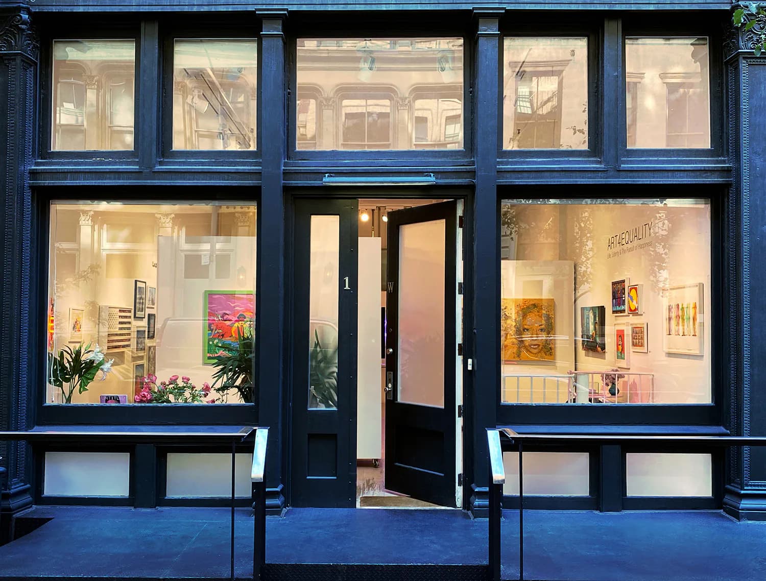 Storefront of Untitled Space gallery in Tribeca with dark blue framing, large display windows showing artwork and plants, and a black entrance door.